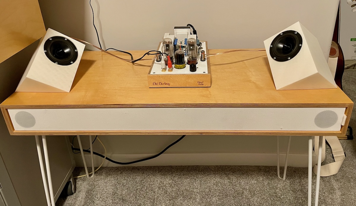 Two speakers on a table with a tube amplifier.